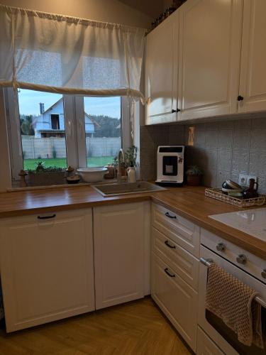 a kitchen with white cabinets and a sink and a window at Dom na Kaszubach, Żuromino 2 0 in Żuromino