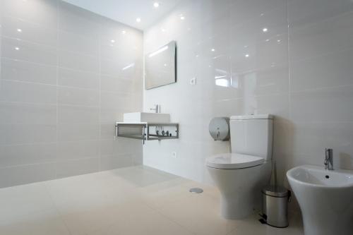 a white bathroom with a toilet and a sink at PeraLux in Pêra