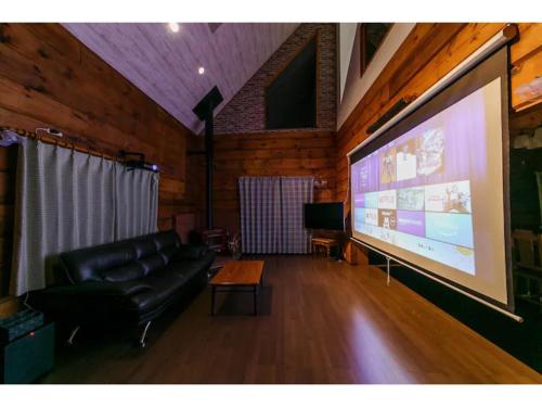 a living room with a couch and a large screen at Log House Seseragi - Vacation STAY 62500v in Tsuru 