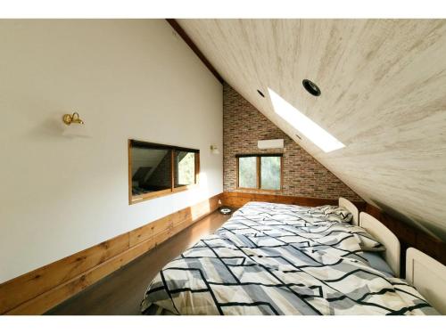 a bedroom with a bed and a brick wall at Log House Seseragi - Vacation STAY 62500v in Tsuru 