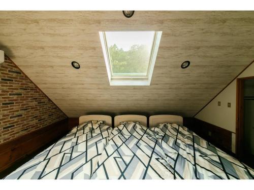 a bedroom with a bed with two chairs and a window at Log House Seseragi - Vacation STAY 62500v in Tsuru 