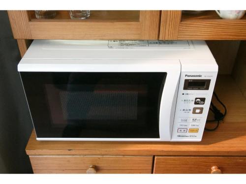 a white microwave sitting on top of a cabinet at Log House Seseragi - Vacation STAY 62500v in Tsuru 