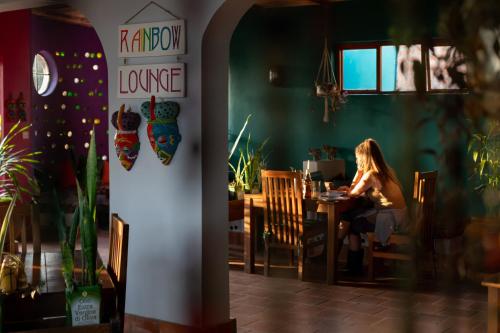 a woman sitting at a table in a restaurant at Chameleon Hill Forest Lodge in Bwindi