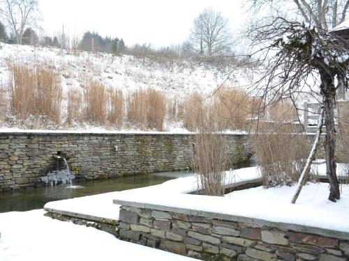 a stone wall in the snow next to a river at Holiday home in Bièvre near town center in Bièvre
