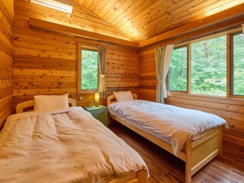 a bedroom with two beds in a log cabin at Runesu Karuizawa - Vacation STAY 92236v in Tsumagoi