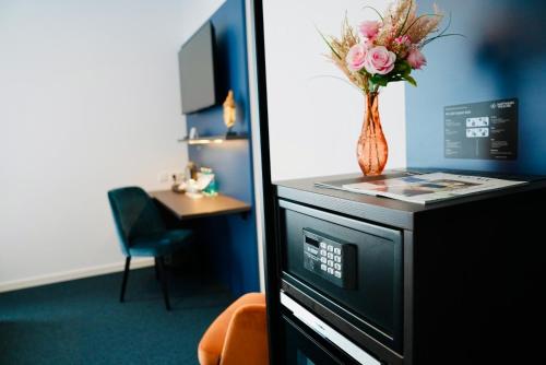 a vase of flowers on a counter in a room at Arthotel Ambassador Wiesbaden - FREE PARKING in Wiesbaden