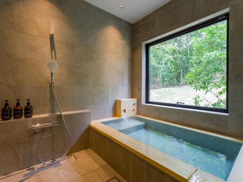 a bathroom with a large tub with a window at Rakuten STAY VILLA Aso Kurokawa -102 1LDK Capacity of 6 persons in Minamioguni