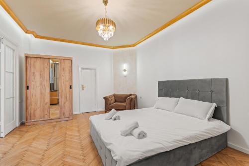 a bedroom with a large bed and a chair at Golden Crown Suite in Bucharest