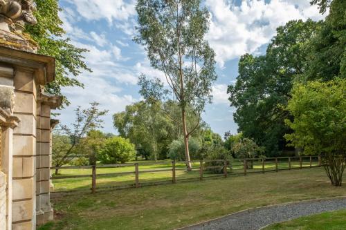 a fence in a park with trees and grass at The Gate House in Peterborough