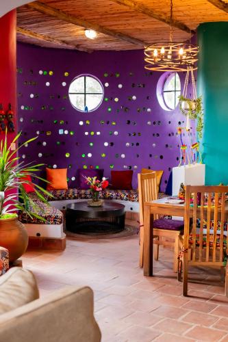 a room with a purple wall with a table and chairs at Chameleon Hill Forest Lodge in Bwindi