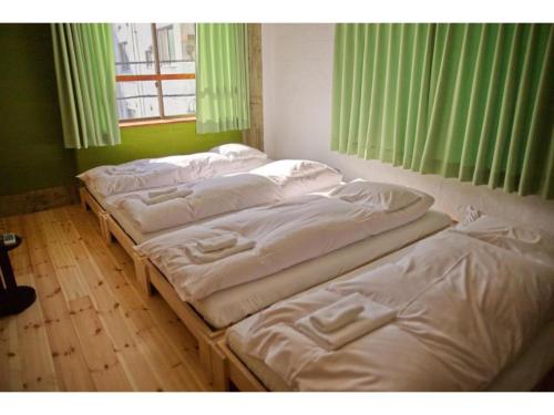 a group of four beds in a room with a window at Konyamachi Guest House Kuku - Vacation STAY 80155v in Takamatsu
