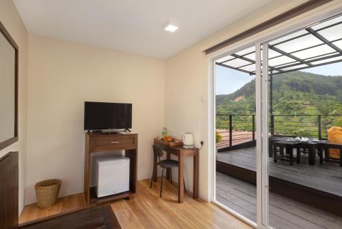 a living room with a flat screen tv and a balcony at The Cubes Ella in Ella