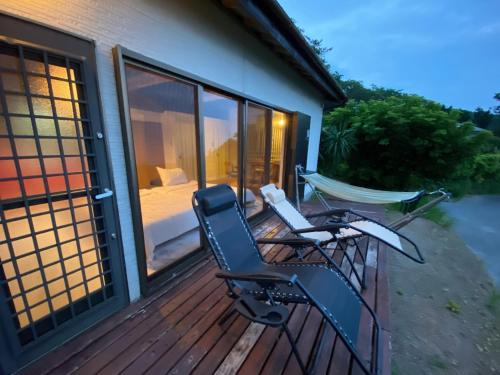 a deck with two chairs and a bed and a hammock at Tiny Camp House Kurage - Vacation STAY 66334v in Kamijinoo