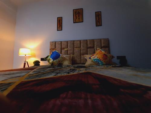 a bedroom with a large bed with pillows and a lamp at Cozy and Tranquil nest with wifi and homely care in Greater Noida