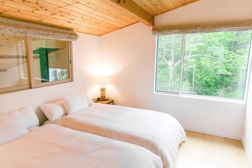 a bedroom with two beds and a window at KARUIZAWA Funny house - Vacation STAY 69541v in Kutsukake