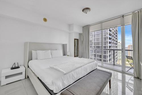 a white bedroom with a bed and a large window at Icon Brickell High Floor Condo with Bay and Pool view 5 star SPA in Miami