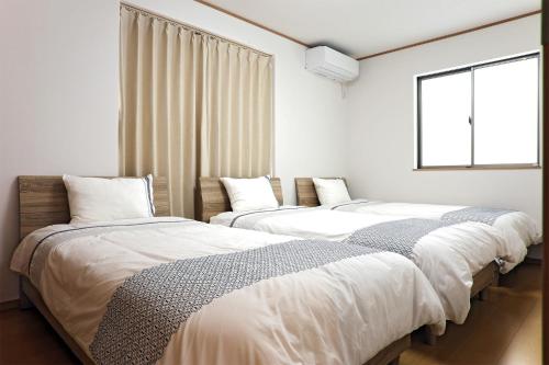 two beds in a room with a window at iruka - Vacation STAY 83037v in Nago