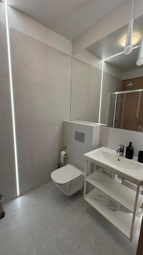a white bathroom with a toilet and a sink at Sandy Apartment Dzwinów 3 Sand and Dunes Sauna Grota Solna Siłownia in Dziwnów