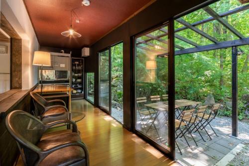 a room with large windows and a table and chairs at Mori no yadori Nasu bettei Maruyama - Vacation STAY 13190 in Nasu-yumoto