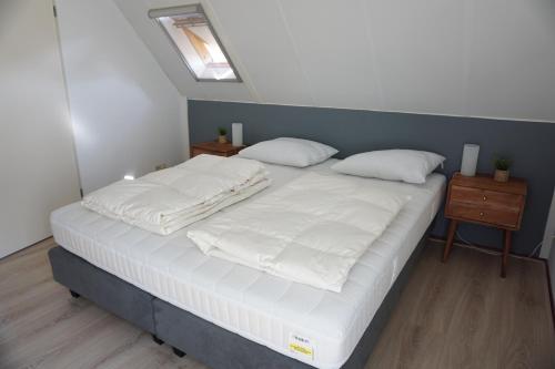 a large bed with white sheets and pillows on it at Kustverhuur, Park Schoneveld Stern 208 in Breskens