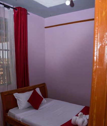 a small bedroom with a bed with a red curtain at 1br 2br and 3br Klaire's apartments in Kisumu