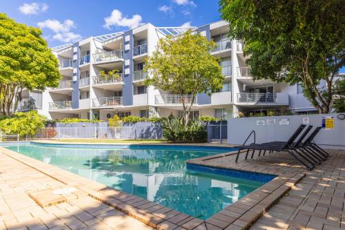 an apartment with a swimming pool in front of a building at Stylish Heritage 2BR Loft near City and River with Pool and Free Parking in Brisbane