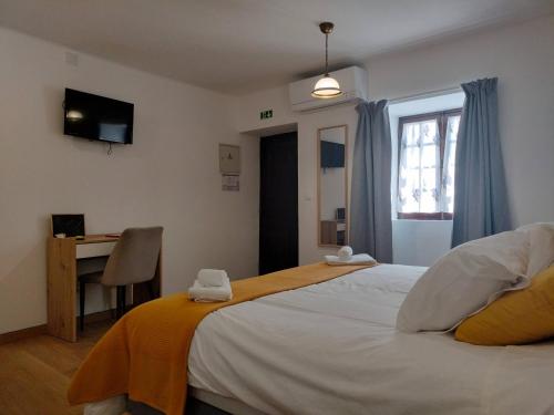 a bedroom with a large white bed and a window at Stone House in Oliveira do Hospital