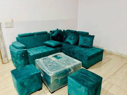 Una sala de estar con un sofá verde y una otomana. en Stay Farm house Villa with pool in Gurgaon, en Bhundsi