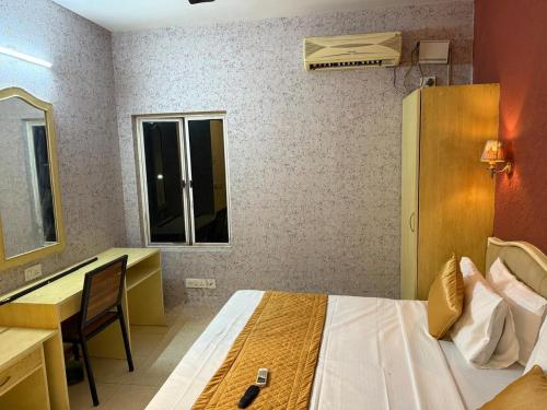 Un dormitorio con una cama, un escritorio y un espejo. en Western e-Inn, en Bangalore