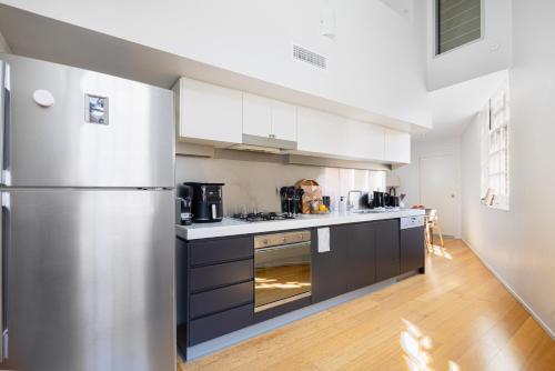 a kitchen with a stainless steel refrigerator at Stylish Heritage 2BR Loft near City and River with Pool and Free Parking in Brisbane