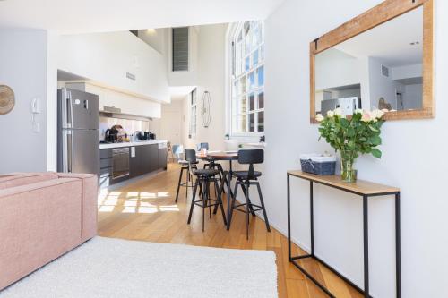 a kitchen and living room with a mirror on the wall at Stylish Heritage 2BR Loft near City and River with Pool and Free Parking in Brisbane