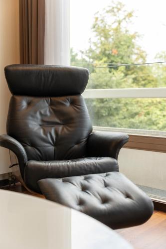 a black leather chair sitting in front of a window at Pakat Residences in Vienna