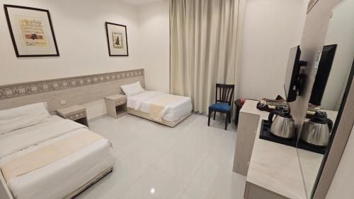 a hotel room with two beds and a flat screen tv at فندق رحاب الرائد in Al ‘Utaybīyah