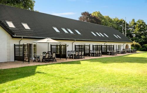 a white building with tables and chairs in a yard at 3 Bedroom Nice Apartment In Nimtofte in Nimtofte