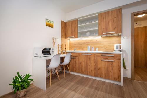 a kitchen with wooden cabinets and a table and chairs at Apartmánový dom Štiavnica in Liptovský Ján