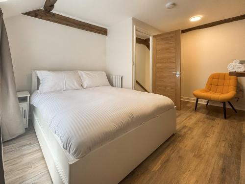a bedroom with a white bed and an orange chair at Apartment Two - Uk49592 in Bala