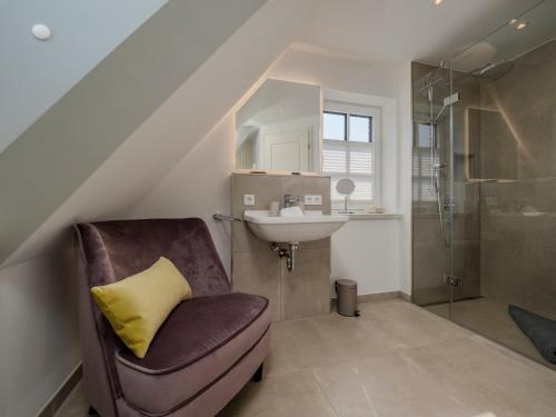 ein Badezimmer mit Waschbecken, Stuhl und Dusche in der Unterkunft Südwind's Greta & Sylt in Sylt