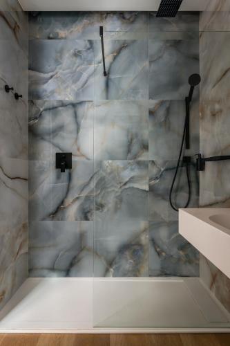 a bathroom with a shower with a marble wall at BYPILLOW California in Málaga