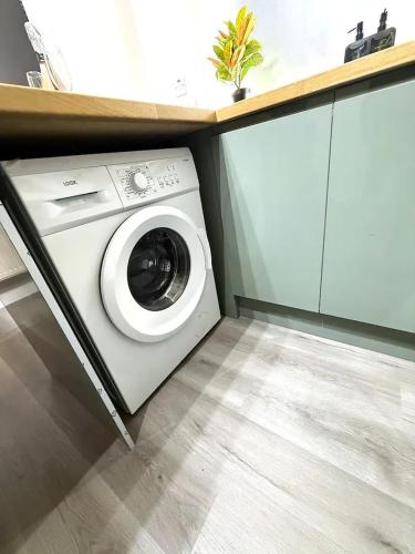a white washing machine in a kitchen with a counter at Stylish 3BR 18mins to Peak District,Free, Parking Wifi,Netflix ,Sky Sports in Ashton under Lyne