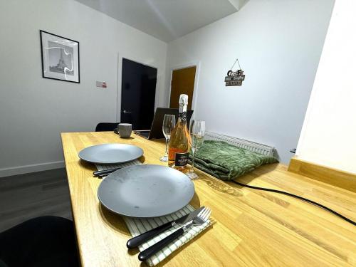 a wooden table with two plates and a bottle of wine at Stylish 3BR 18mins to Peak District,Free, Parking Wifi,Netflix ,Sky Sports in Ashton under Lyne