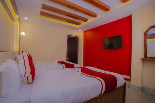 a bedroom with two beds and a red wall at OYO 160 Hotel Shraddha Palace in Kathmandu
