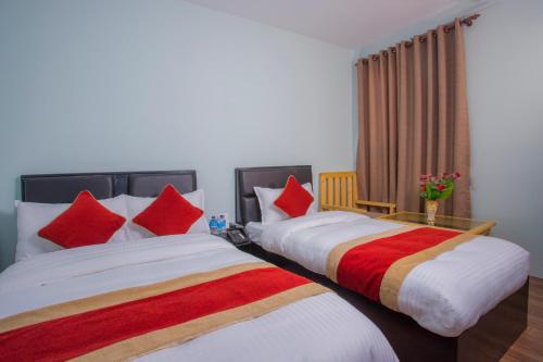 two beds in a hotel room with red and orange pillows at OYO 260 Hotel Cultural Inn in Kathmandu