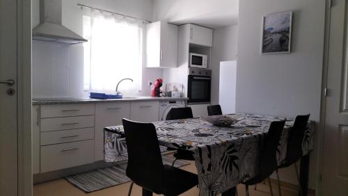 a kitchen with a table with black chairs and a kitchen with white cabinets at Casa T3 Área Metropolitana do Porto in Carregosa