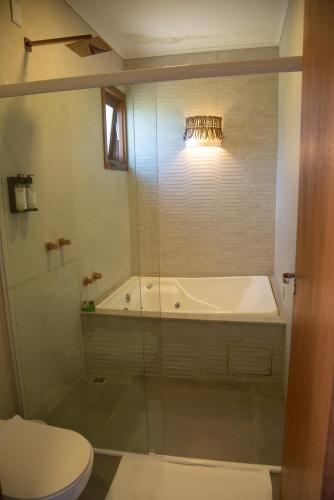 a bathroom with a shower and a tub and a toilet at Pousada Paraíso Gaia in Praia do Rosa