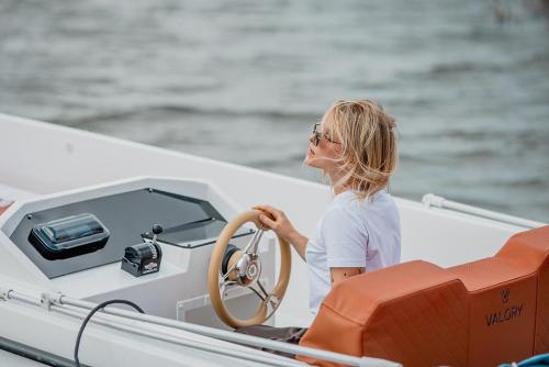 a woman sitting on a boat with a steering wheel at Hotel Marina Club in Olsztyn