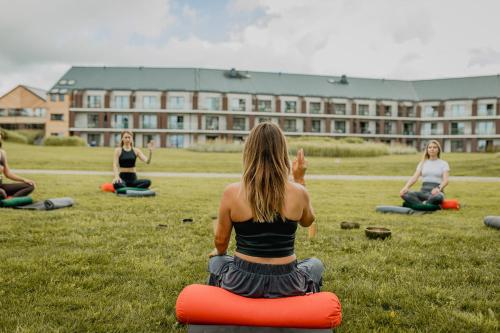 a group of women sitting in a field doing yoga at Hotel Marina Club in Olsztyn