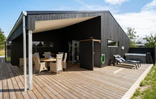 a black building with a deck with a table and chairs at Gorgeous Home In Saltum With Wifi in Saltum