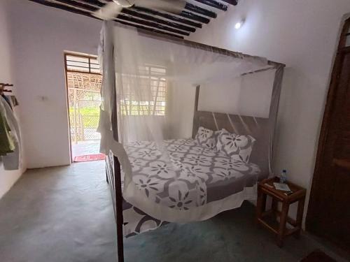 Un dormitorio con una cama con dosel en una habitación. en Hakuna Matata Bungalows, en Jambiani