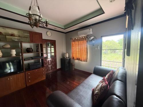 Una sala de estar con un sofá y un televisor. en บ้านสวนอยุธยาคลองสระบัว, en Phra Nakhon Si Ayutthaya