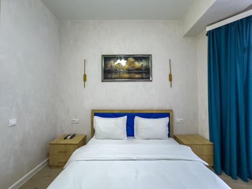 a bedroom with a large bed with blue curtains at Deluxe Rooms and Apartments Near Metro in Tbilisi City